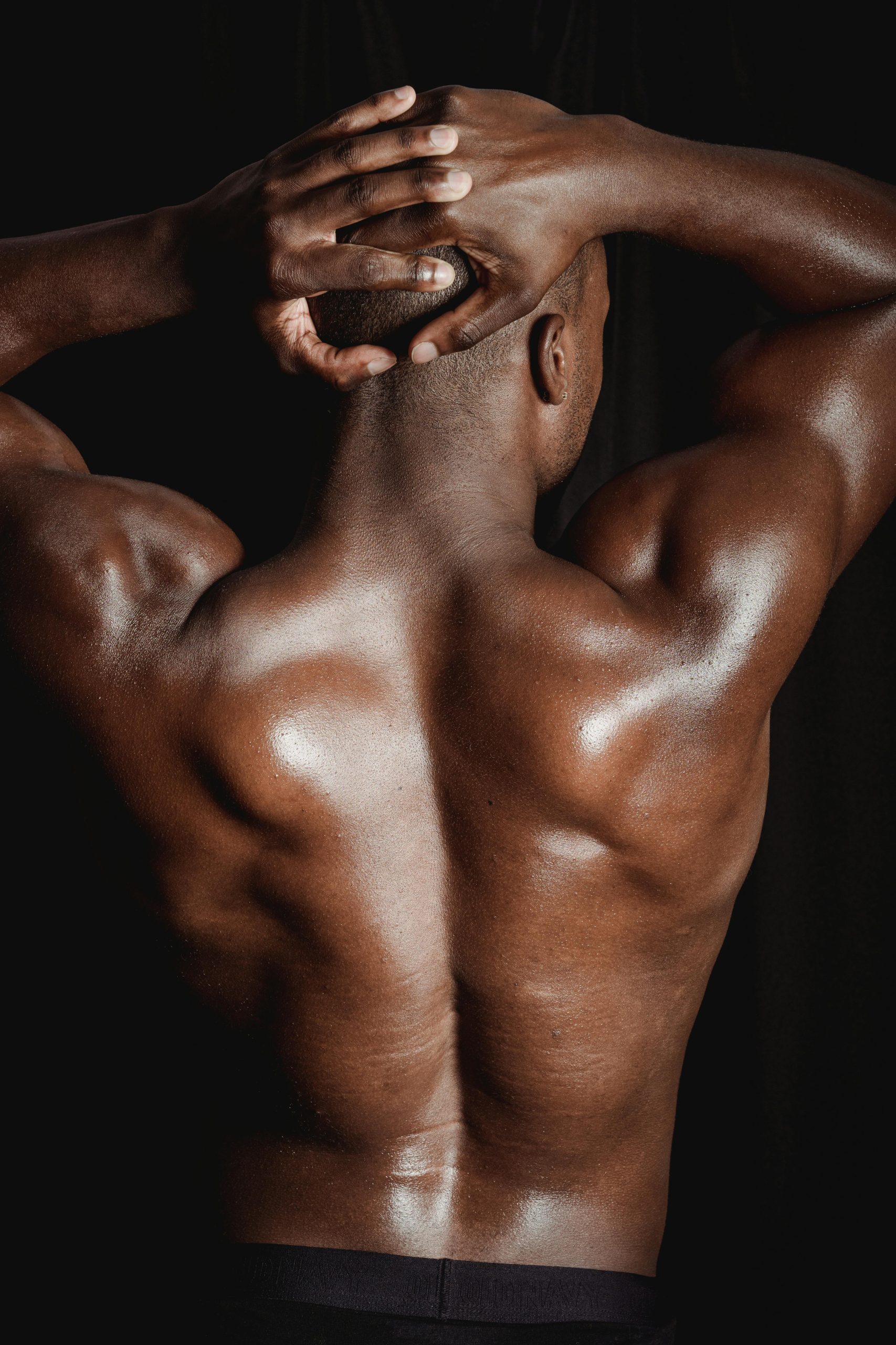 Shot of a shirtless muscular man flexing his back muscles, displaying strength and fitness.